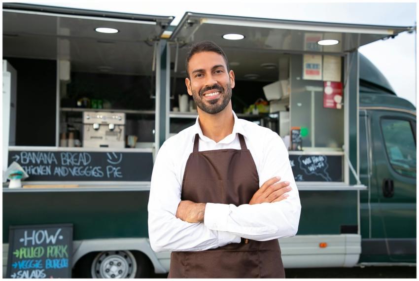 Smiling young ethnic male waiter in apron standing