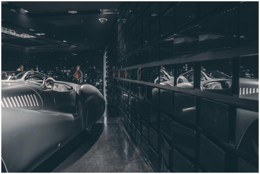 A vintage car displayed in a modern glass-walled s