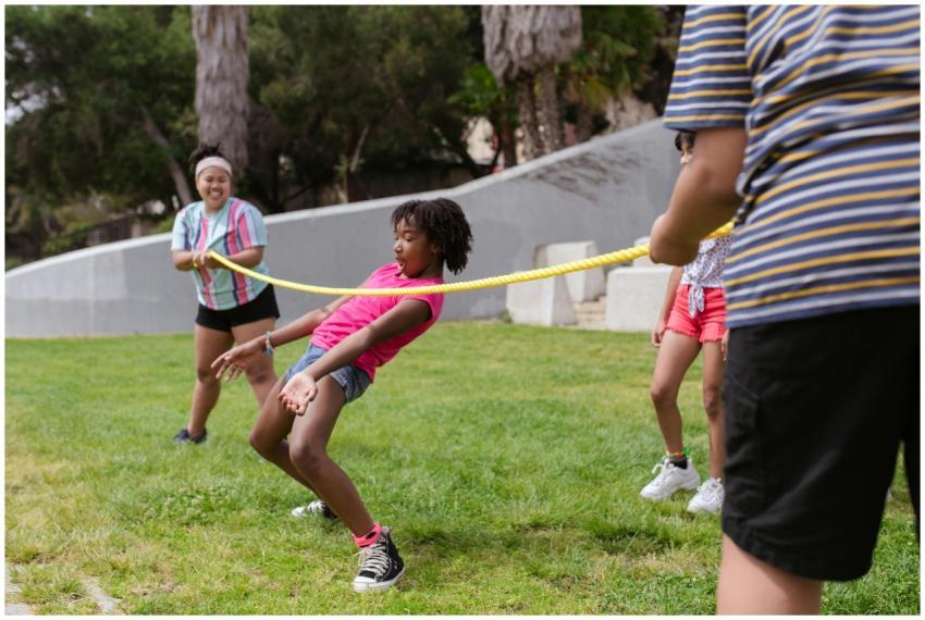 Children enjoy a fun limbo game on the grass at su