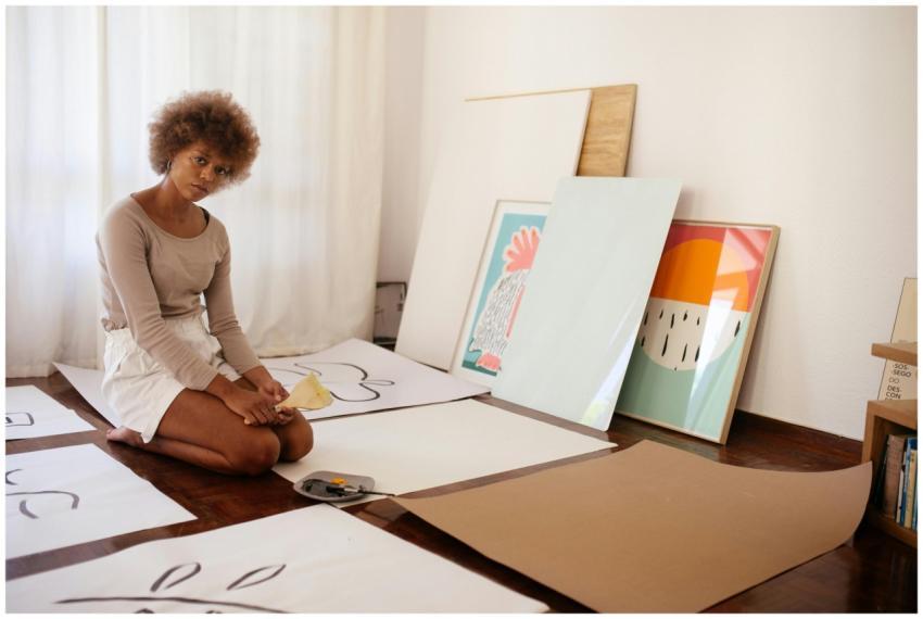 Young woman artist sitting among canvases, thought