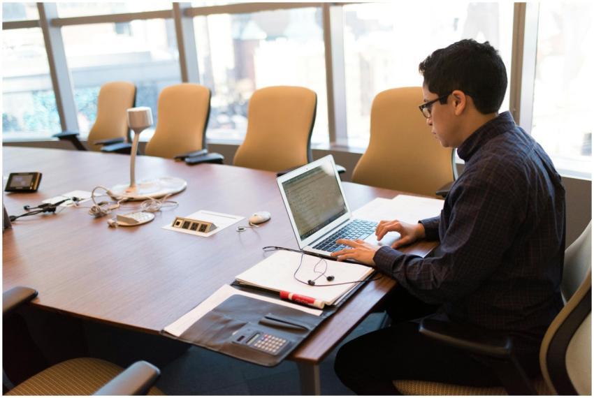 A professional adult sitting at a desk with a lapt