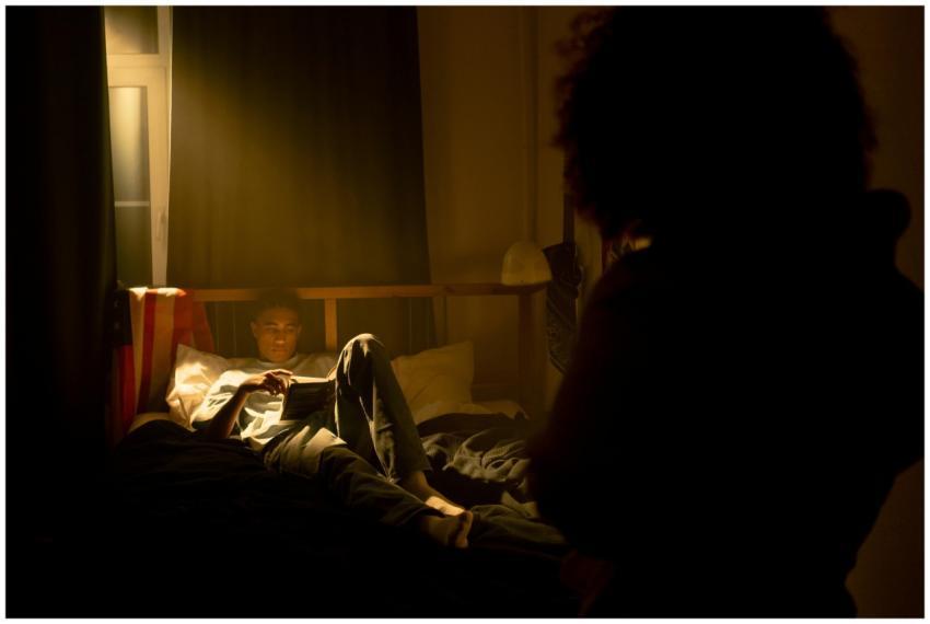 A person reading in a softly lit bedroom, creating