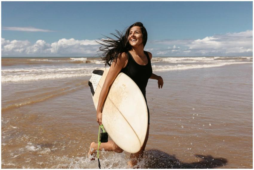 A woman confidently runs through ocean waves, carr