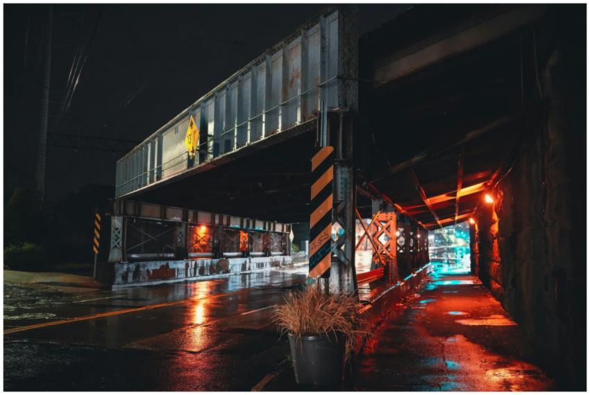 Dimly lit urban underpass at night with rain-soake