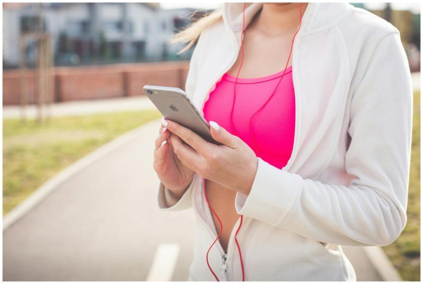 Young woman outdoors using smartphone and earphone