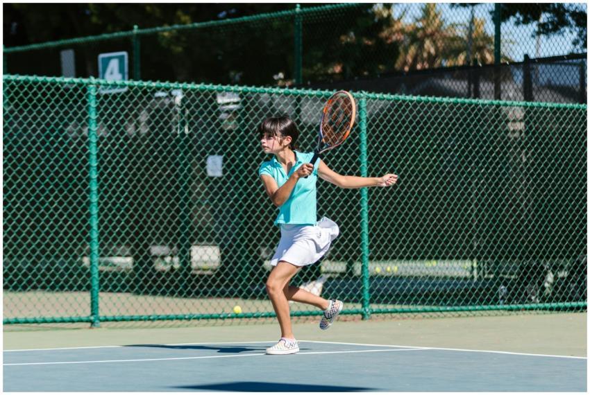 A young girl in action playing tennis on an outdoo
