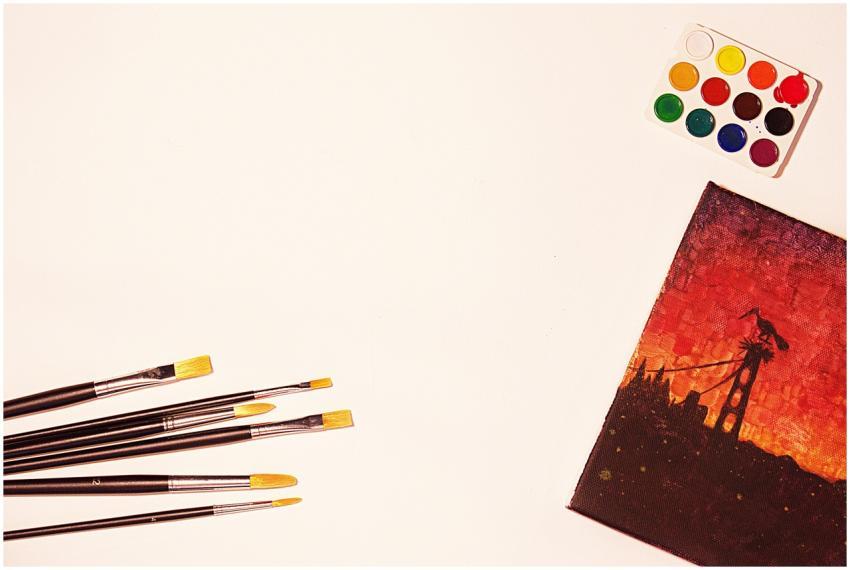 Flat lay of paintbrushes, watercolors, and a vivid