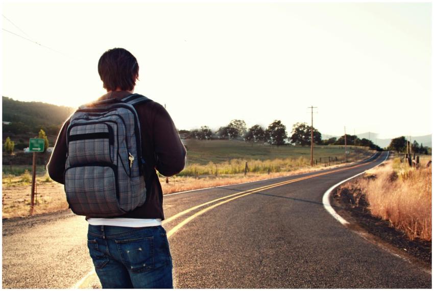 A traveler with a backpack walks on a winding road
