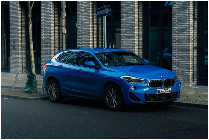 A vibrant blue SUV is parked against an urban bric