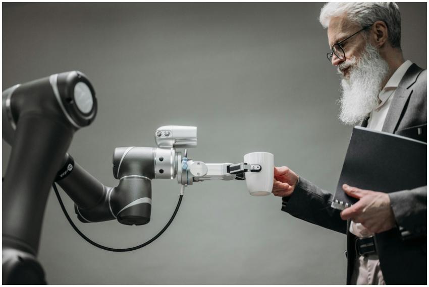 An elderly man receives a cup from a robotic arm i