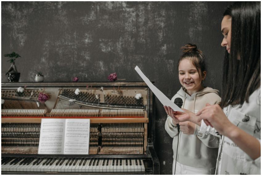 A young girl learning piano with a teacher in a co
