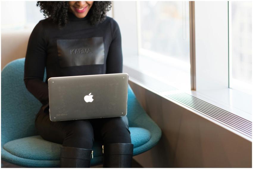 Smiling woman working on a laptop seated by a wind