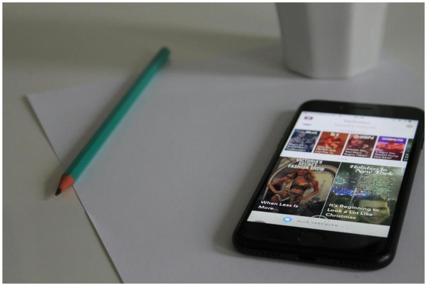 Smartphone displaying news, next to pencil and pap