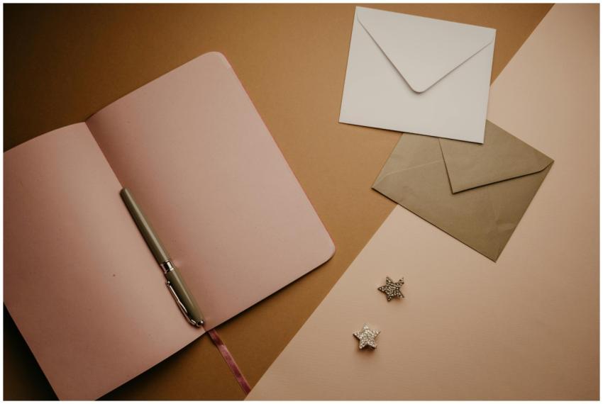 A stylish flat lay featuring an open notebook, env