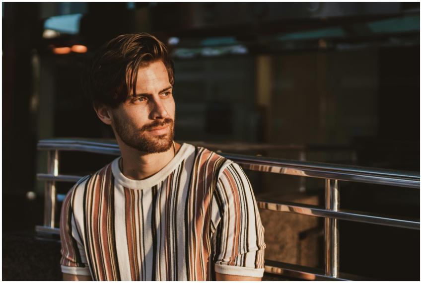 A thoughtful man in a striped shirt bathed in warm