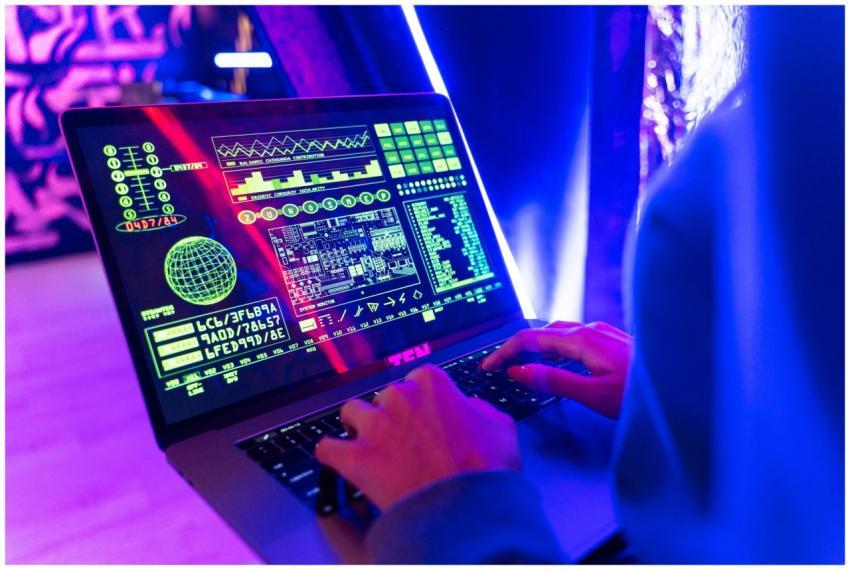 Person typing on a laptop with vibrant digital dat