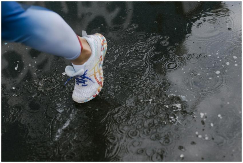 Close-up of a runner's shoe splashing through a pu