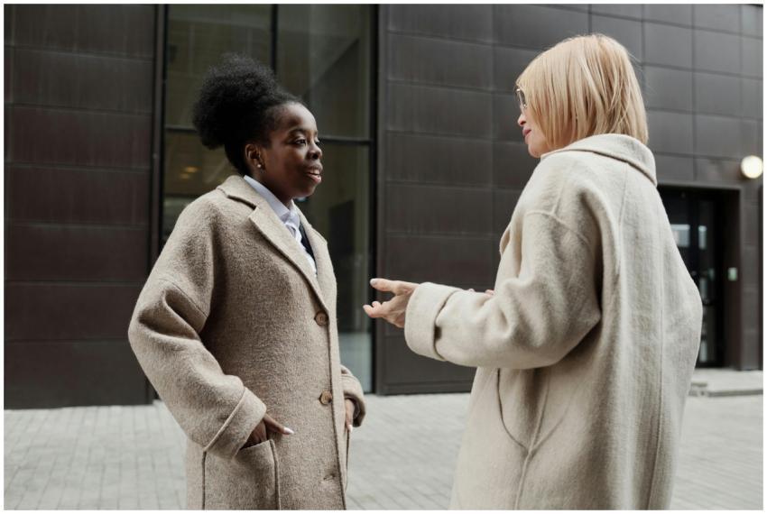 Two businesswomen in coats having a conversation d