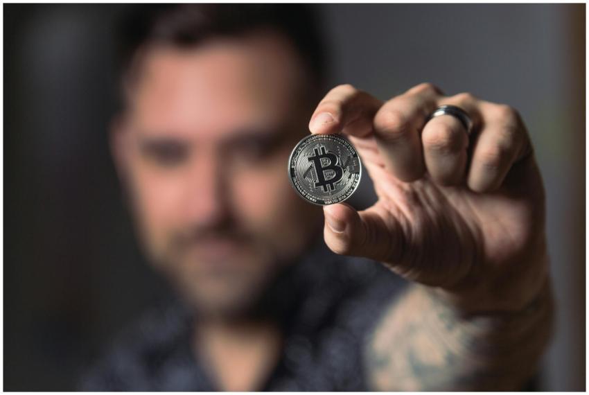 Adult male hand holding a Bitcoin, showcasing cryp