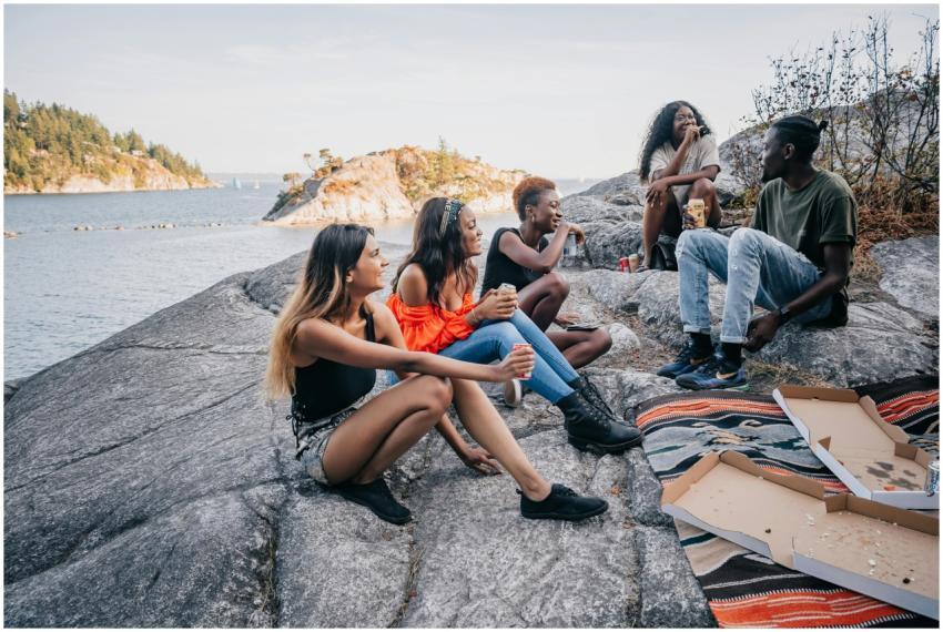 A group of friends relax on rocky seaside cliffs,