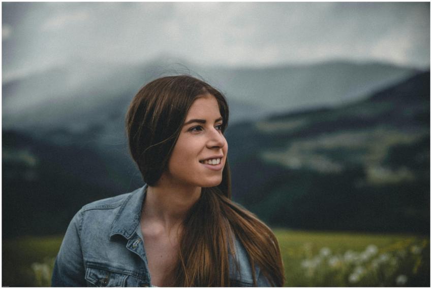 Smiling woman in a denim jacket with mountains in
