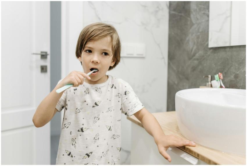 A young blond boy practicing dental hygiene by bru