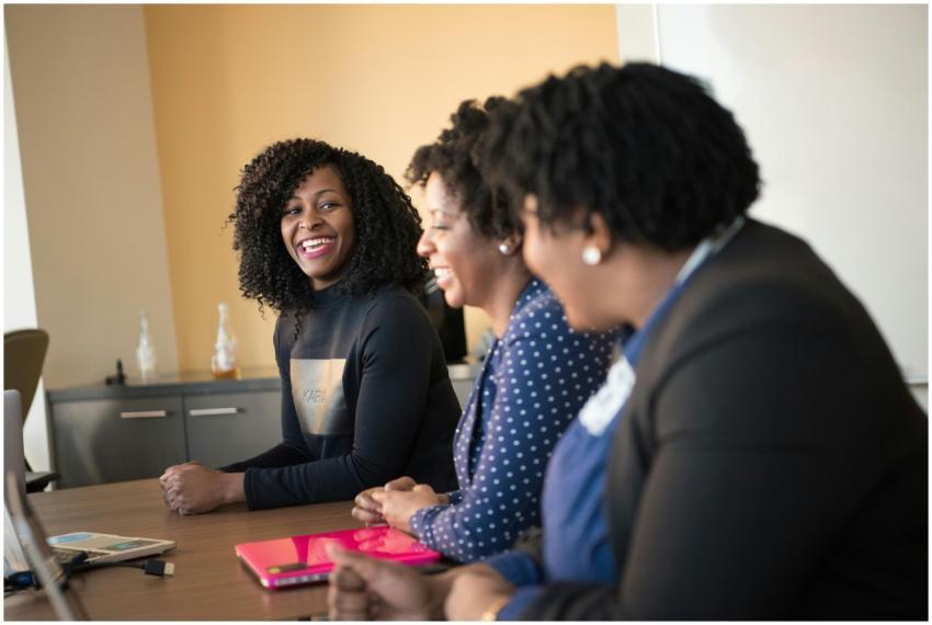 Three black women in a happy office meeting, engag