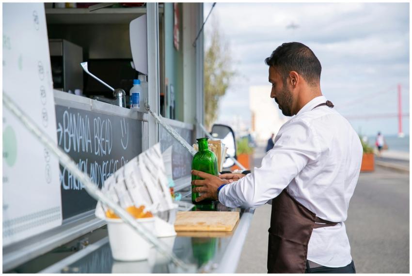 Male vendor prepares drinks at a food truck by the