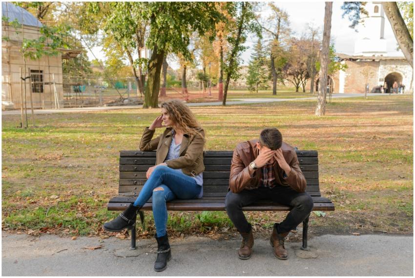 An upset couple seated on a park bench, expressing