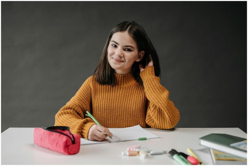 A cheerful student wearing a brown sweater sits at