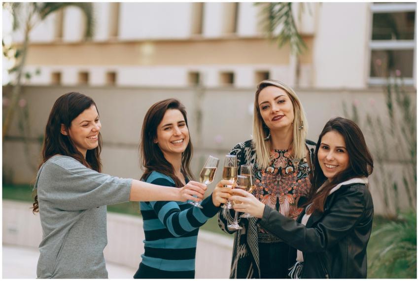 Four women smiling and enjoying a wine toast outdo