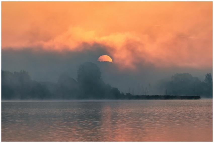 A calm sunrise with mist over a peaceful lake crea