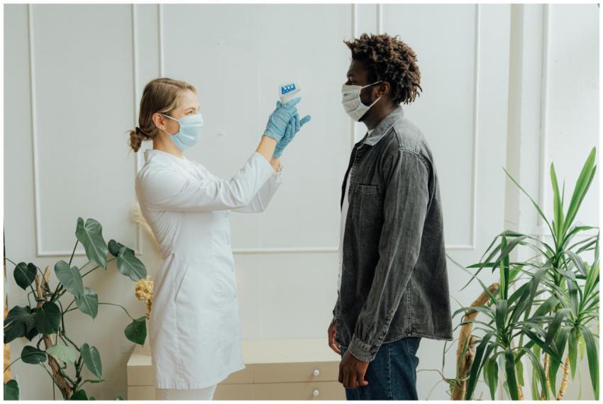 A healthcare professional checks a patient's tempe