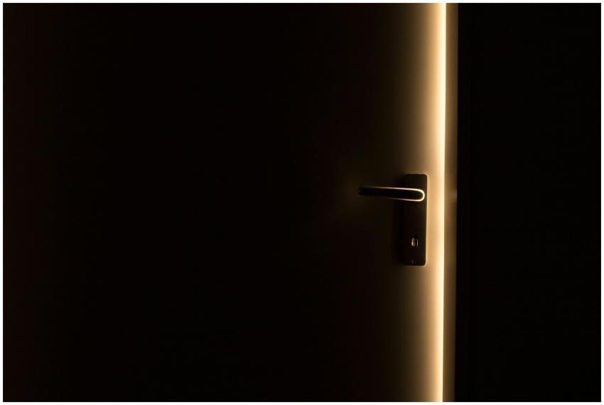 A dark room with a door slightly ajar, revealing a