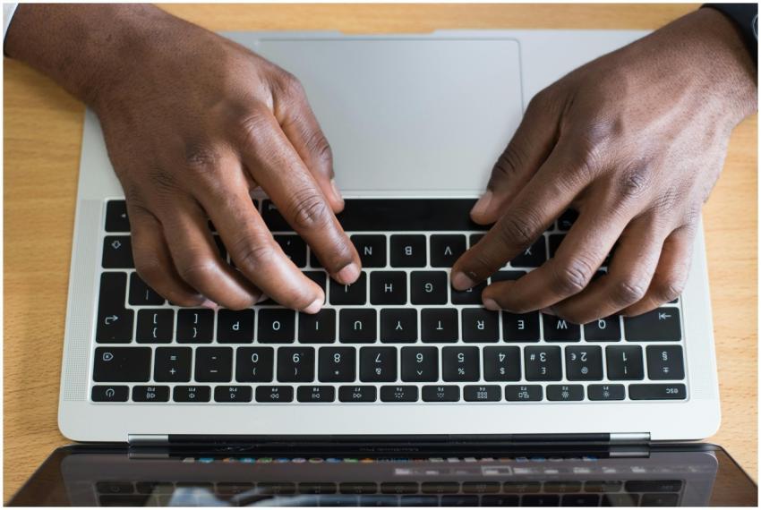 Hands typing on a laptop keyboard, showcasing mode