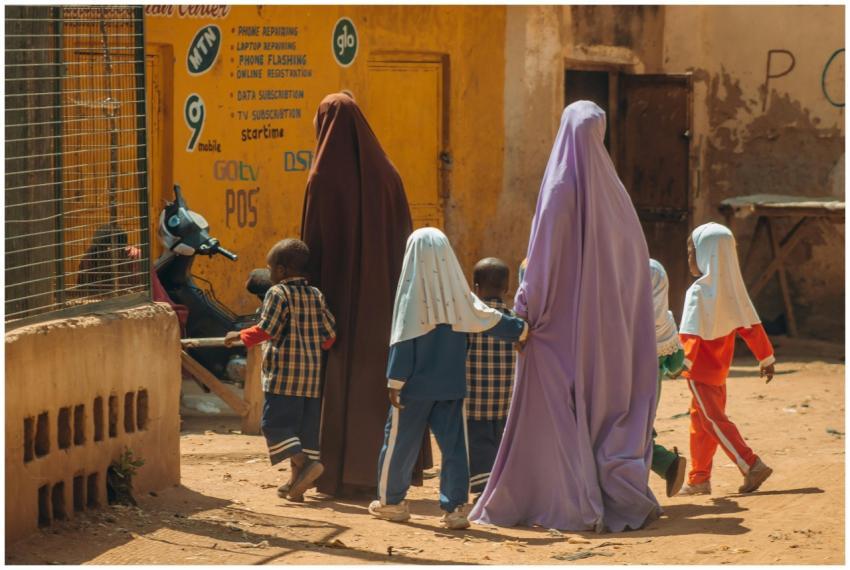 Two women in traditional attire walk with children