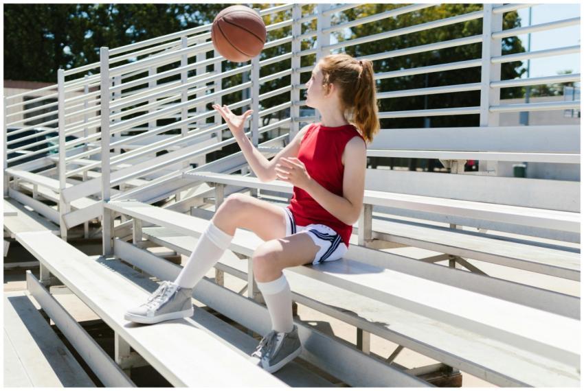 A young girl in sportswear sitting on bleachers ou