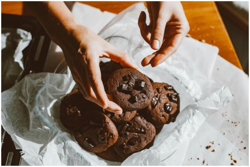 A person holding freshly baked chocolate cookies,