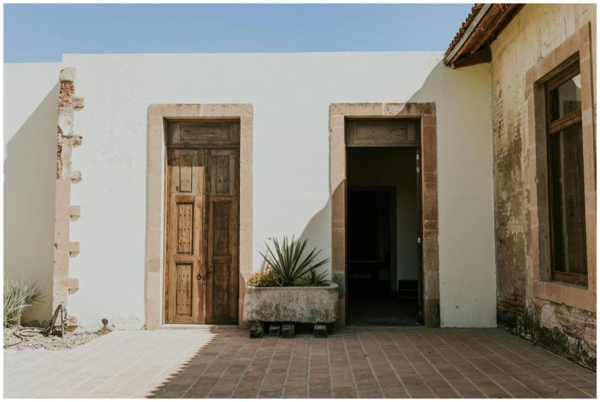 Rustic wooden doors in a sunlit courtyard with ter