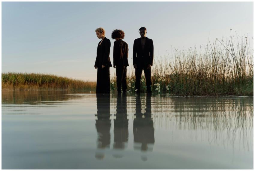 Three models in black outfits posing in water at s