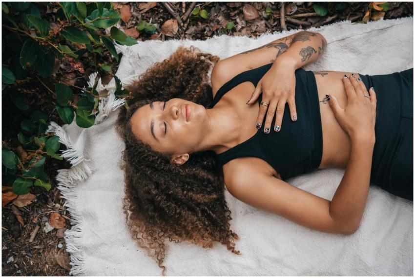 Woman with curly hair relaxing outdoors, lying on