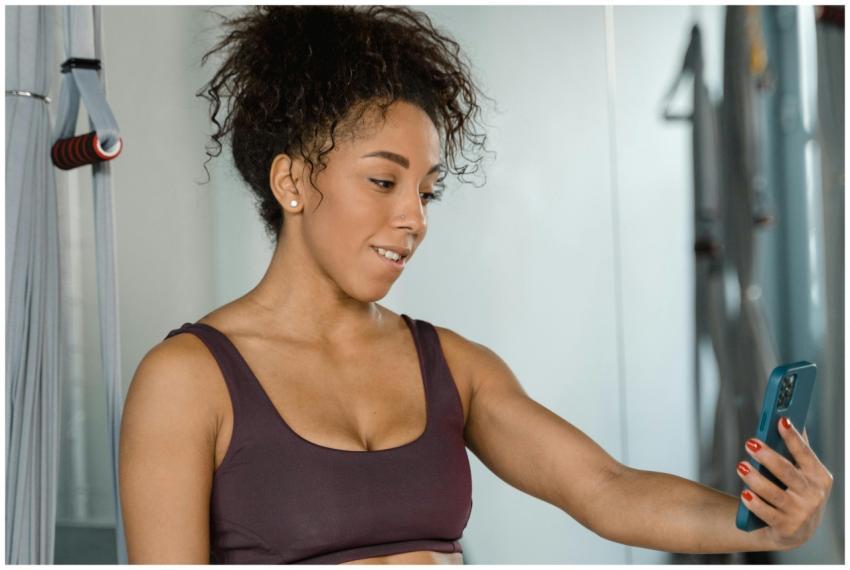 Woman in activewear using smartphone indoors at gy