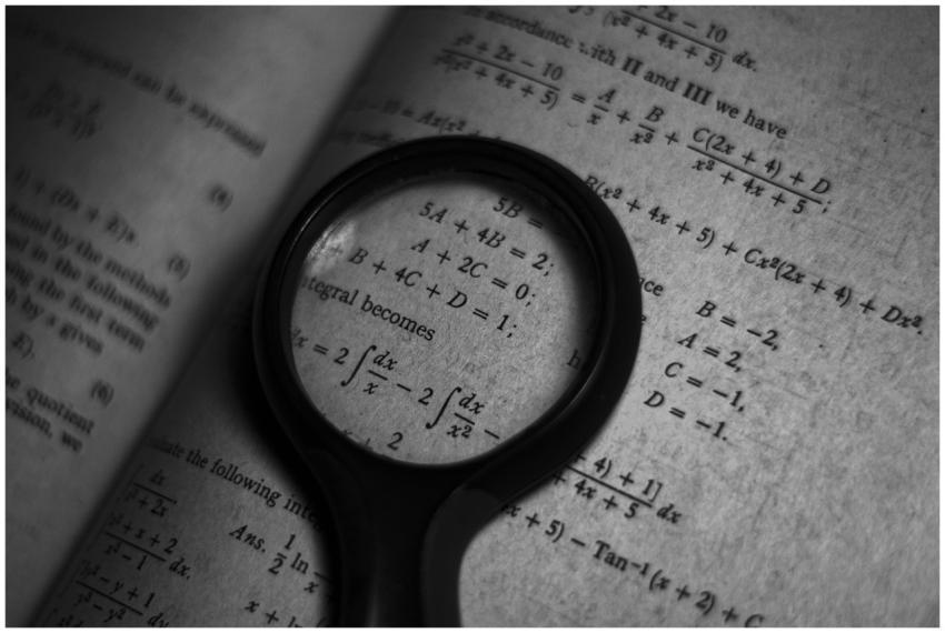 A magnifying glass focuses on mathematics formulas