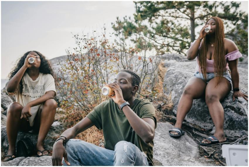 Three friends enjoying drinks outdoors, sitting on