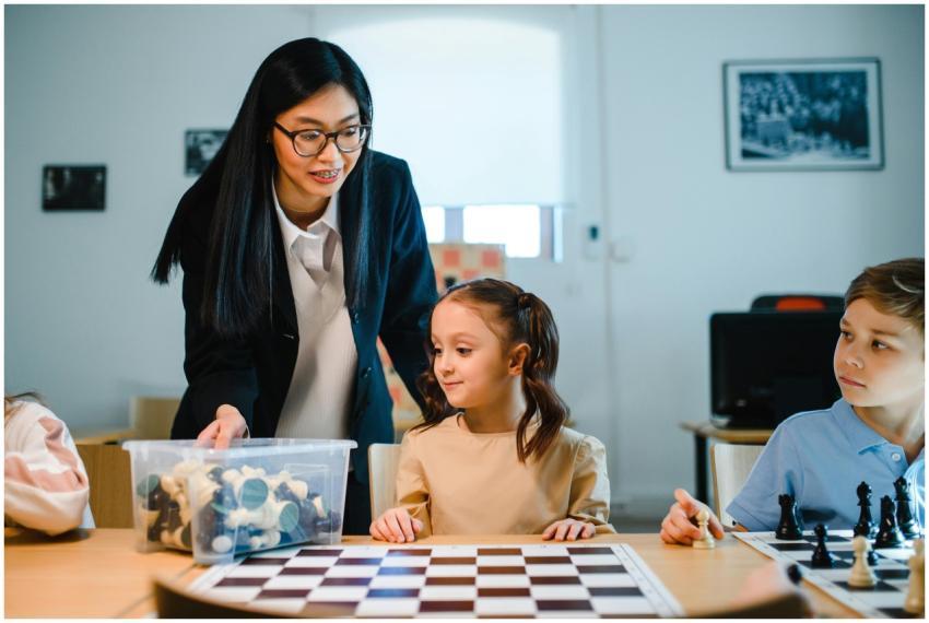 Teacher instructing young students in chess at sch