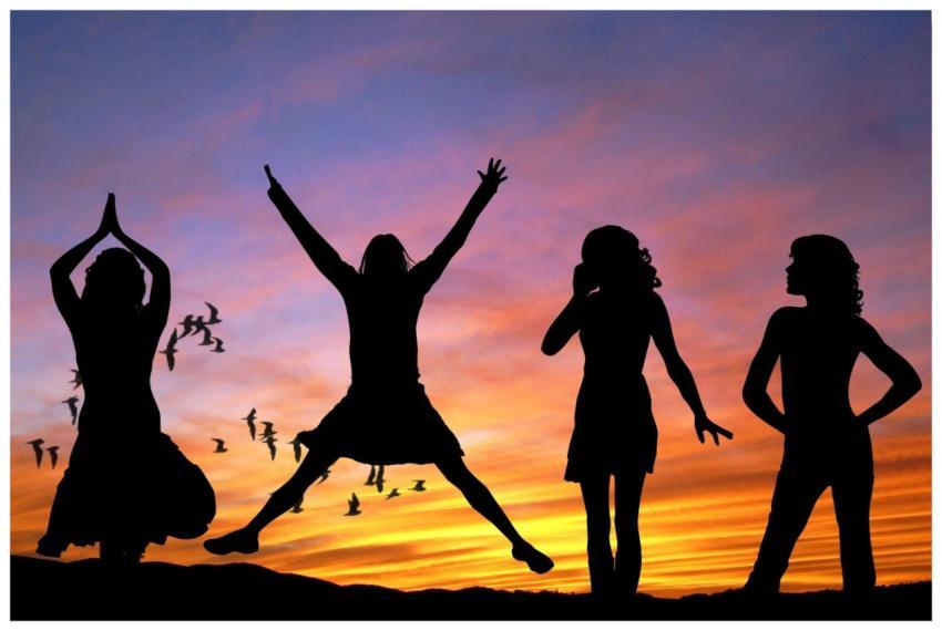 Silhouetted group of women joyfully jumping and po