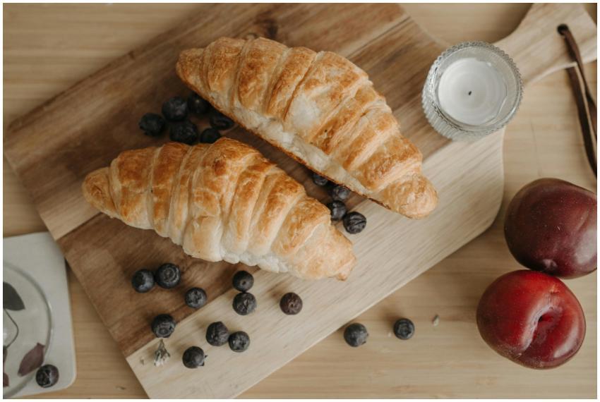 Top view of croissants with blueberries, plums, an