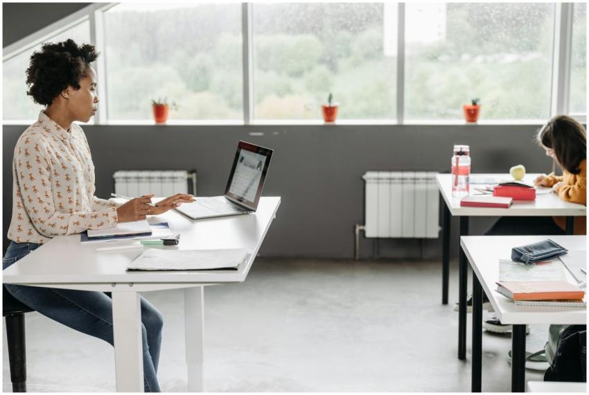 A teacher focused on her laptop in a bright, moder