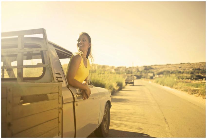 A woman smiles joyfully while riding in a vintage