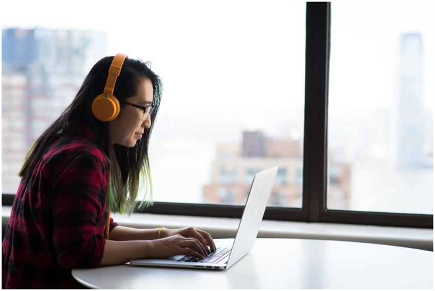 Asian woman with headphones using laptop for remot